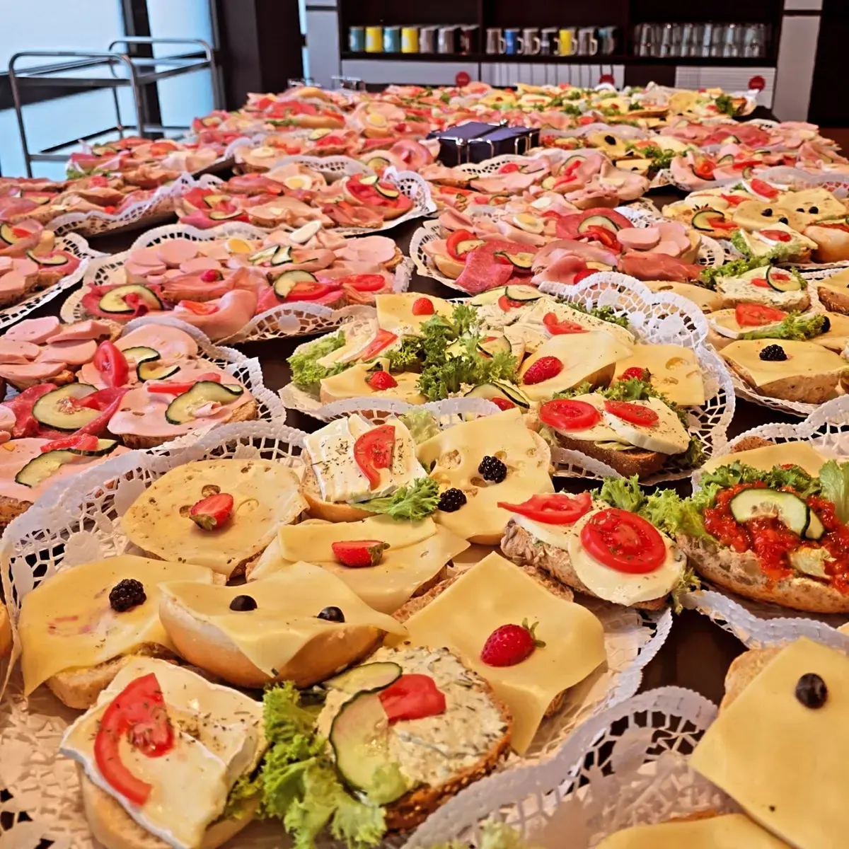 Große Platte mit belegten Brötchen: Schinken, Käse, Salat, Erdbeeren