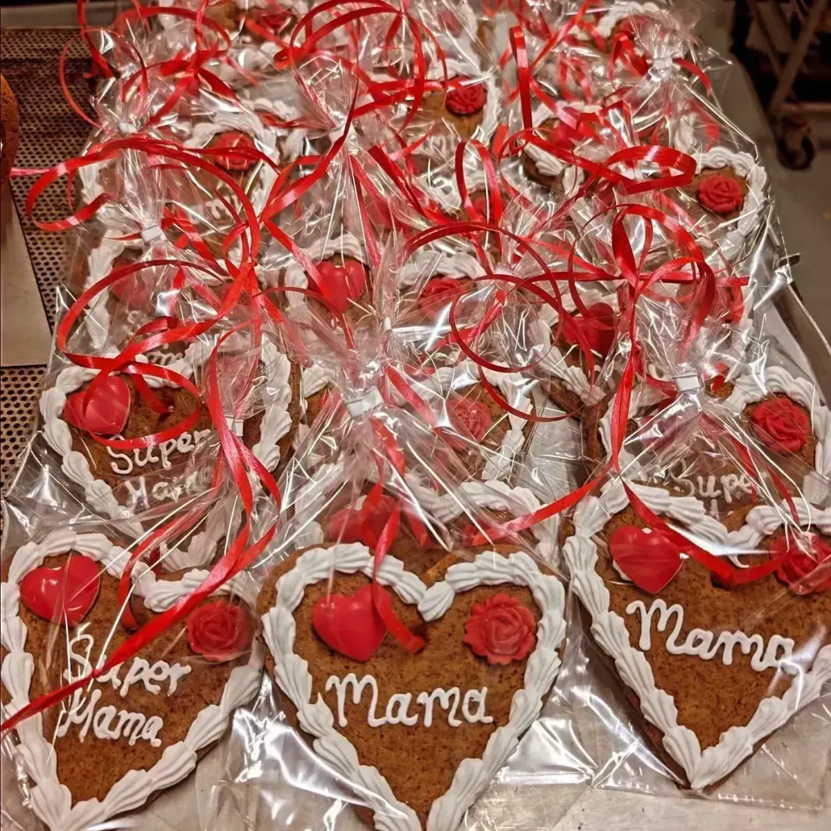 Lebkuchenherzen mit Zuckerguss-Schrift und roten Rosen, in Folie verpackt