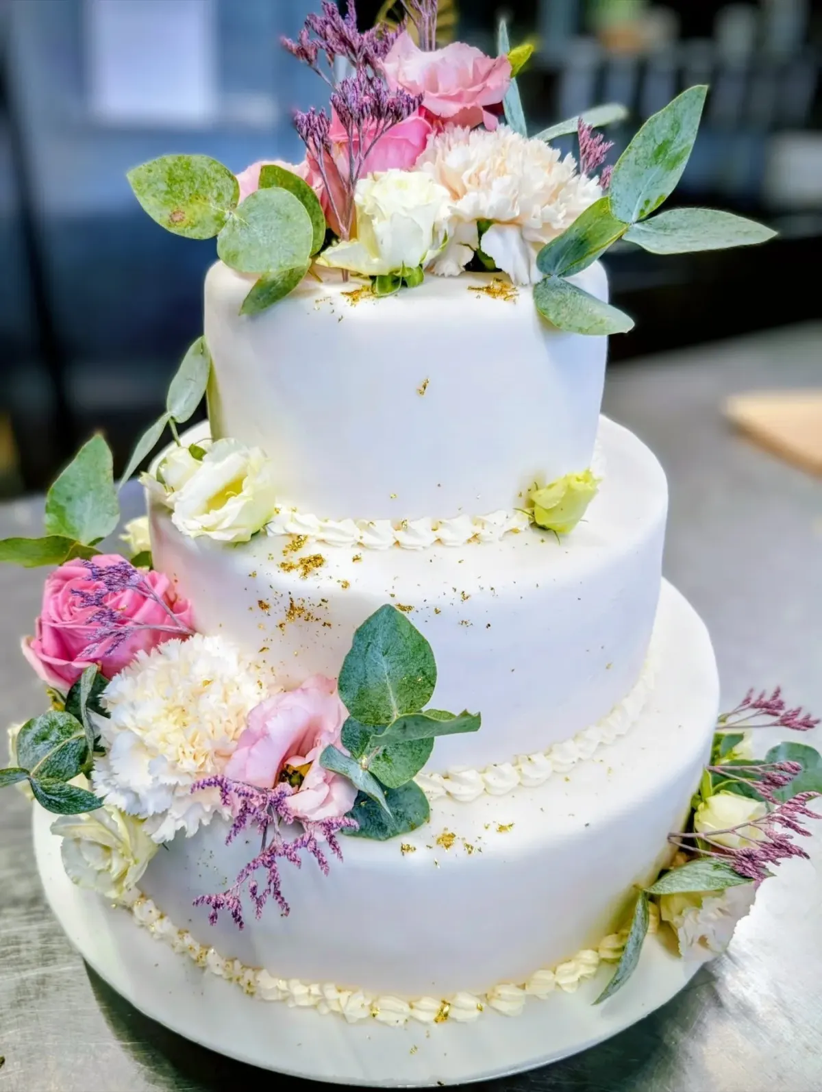Hochzeitstorte von der Seite: Buttercreme, Schokoladen-Drip und Rosen