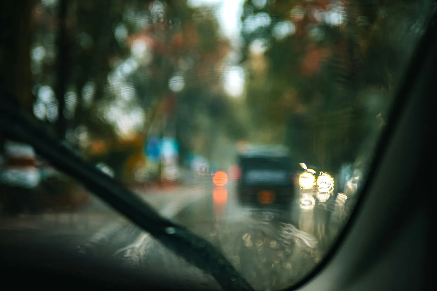 Blick durch eine Windschutzscheibe bei Regen auf die Straße